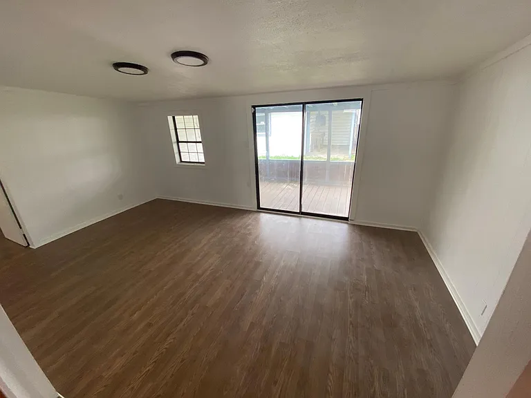 Den with door to back porch and yard