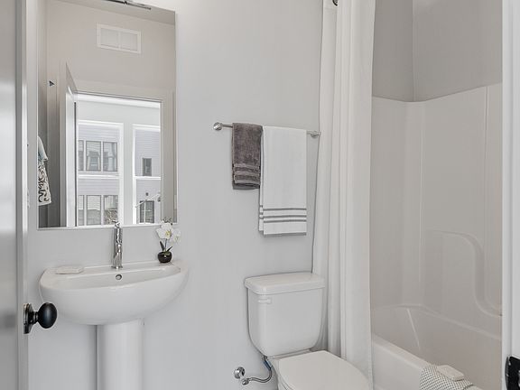 Crisp and modern full bath on the main level_perfect for guests or first-floor living, complete with tub/shower combo and sleek pedestal sink.
