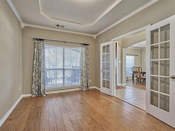 The office has double French doors and a view of the front yard.