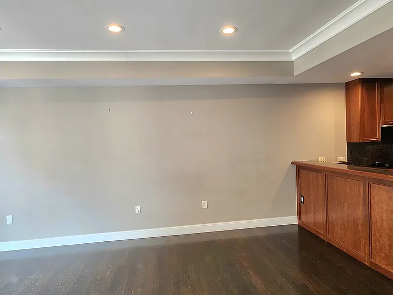 View from the east wall of the main living area toward the opposing wall, with kitchen bar visible.