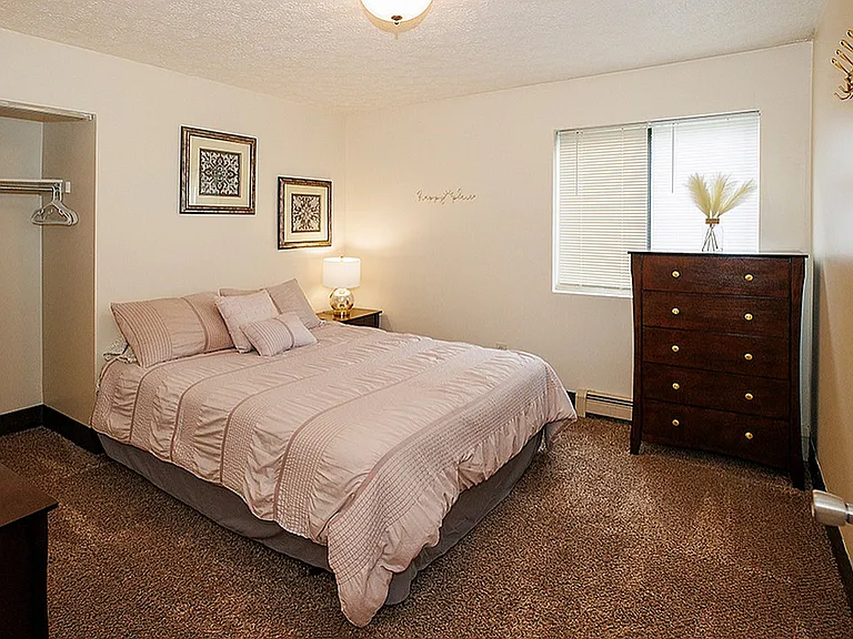Cozy bedroom with elegant decor featuring a plush bed, warm lighting, and a stylish dresser creating an inviting atmosphere.