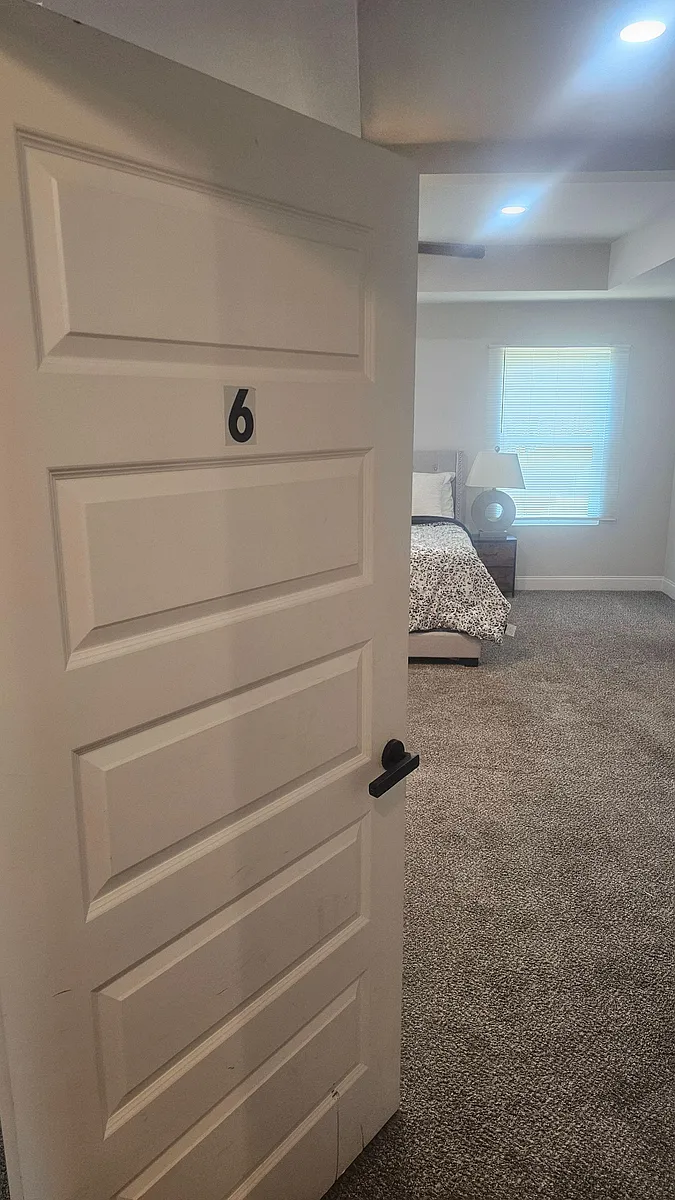 Carpeted bedroom with a large window, recessed lighting, and space for a full bed plus nightstand. - Stonewood