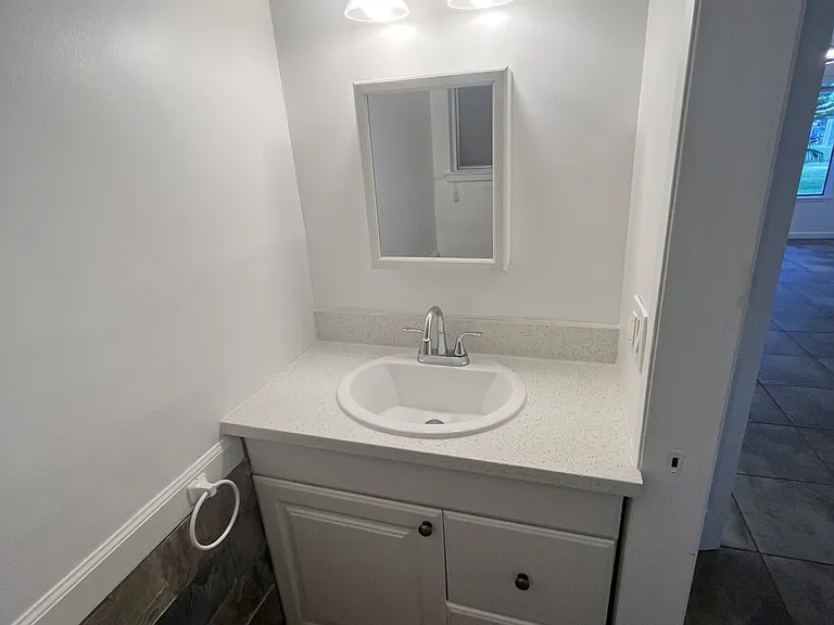 guest 1/2 bath on main floor, features quartz counter top. Mirror is a medicine cabinet with storage. Updated lighting and fixtures. Special 1/2 wall treatment. Nice bright white paint
