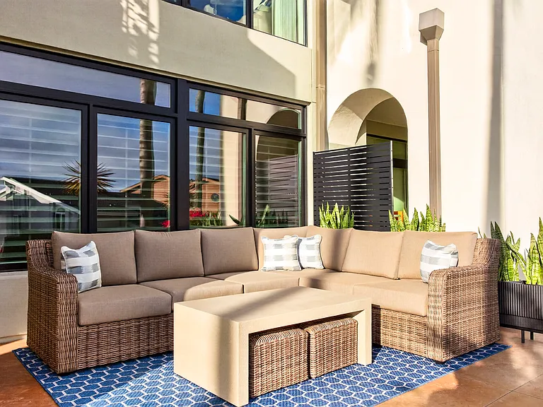 Open air patio with sectional couch, table, and ottomans