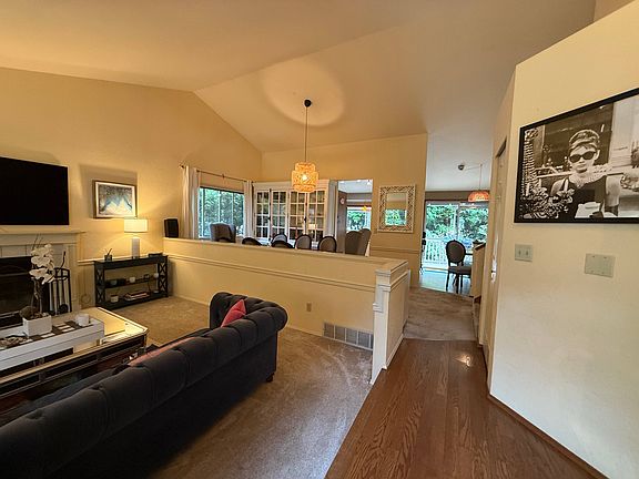 Welcoming foyer flows into a bright, open-concept living room. The spacious living room features vaulted ceilings and abundant natural light. Just a few steps up, the elevated dining area overlooks the main living room.