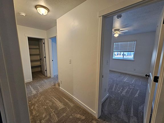 Upstairs hallway connects two bedrooms and large storage closet with built-in shelves