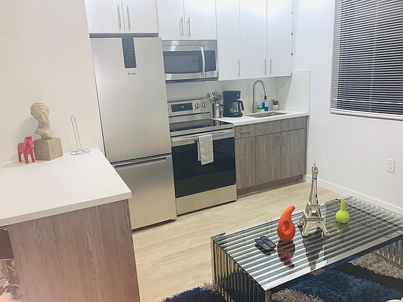 Living space Modern Furniture with Pops of Color Stainless Steel Appliances Coffee Maker Micro wave Dinner ware Silverware Cooking Utensils Pots