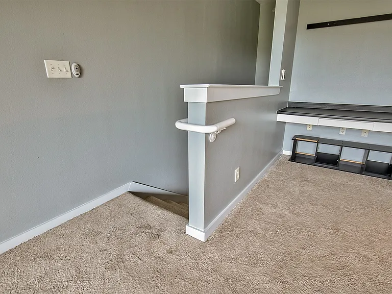 Carpeted interior area with light gray walls, white trim, and a built-in desk or shelving unit featuring a dark countertop