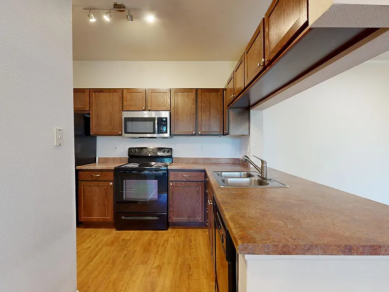 Apartment kitchen with wood-style flooring.