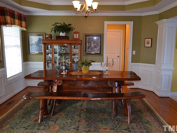 Large Dining Room with hardwood floors and trey ceiling, pillars, two windows w/ blinds and open concept living space with views of the family room.