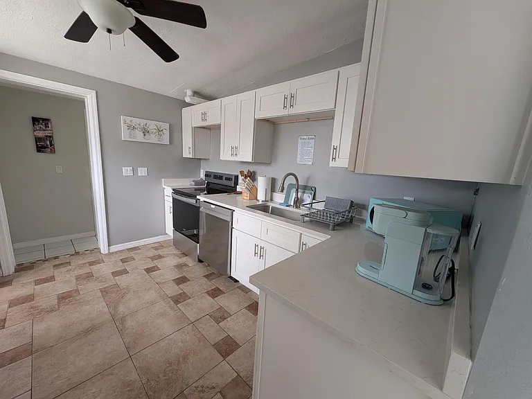Efficient kitchen with ample white cabinetry, generous counters, and stainless appliances plus a double sink for easy prep.