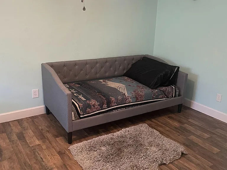 Furnished bedroom with a daybed, ceiling fan light, and durable wood-look flooring with space for personal storage.
