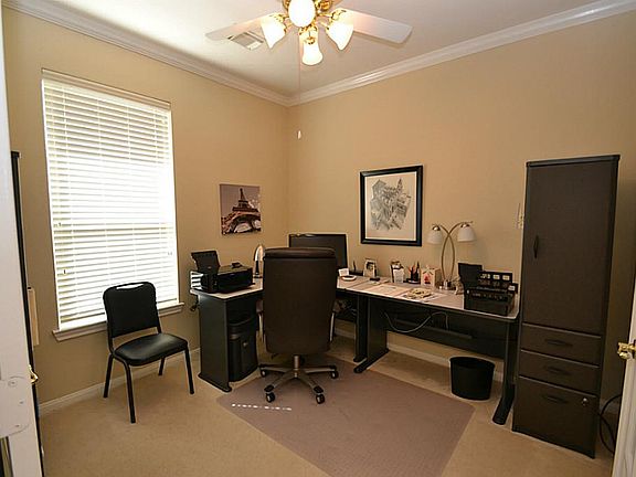 French doors open to the study accented by crown molding and a ceiling fan with light fixture.