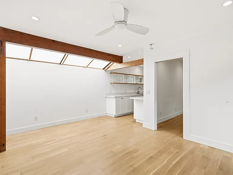 Living room with a view into the bedroom door and kitchen