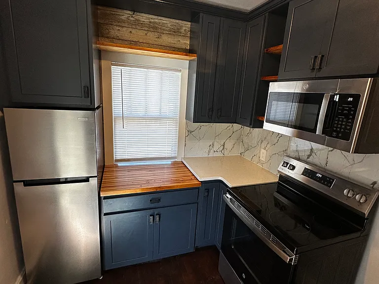 Handmade Butcher block countertop by Stainless fridge. Fun shelf above window.