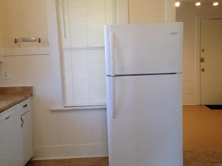 Larger newer refrigerator with ice maker. View of kitchen with porcelain tile flooring. large windows and lots of charming space.