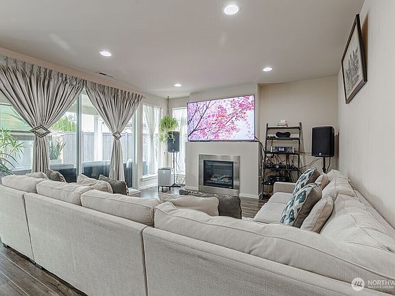 The expansive great room features a cozy gas fireplace and walls of windows, filling the space with natural light and warmth.>