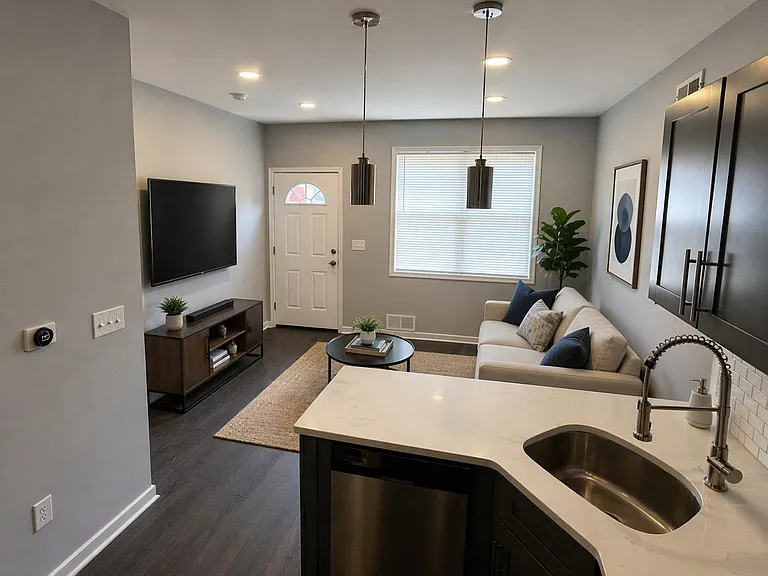 Open-concept living area with a comfortable seating space, large window, and adjacent kitchen peninsula with sink and bar sea