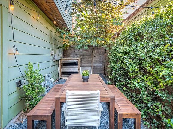 Around the corner from the covered porch is this currated area which is perfect for dining! Crushed granite rocks cover the ground, and greenery surrounds the space. Door on left leads directly into garage for easy maintenance of backyard area.