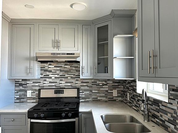 Kitchen with beautiful backsplash and stainless steel stove and fridge.