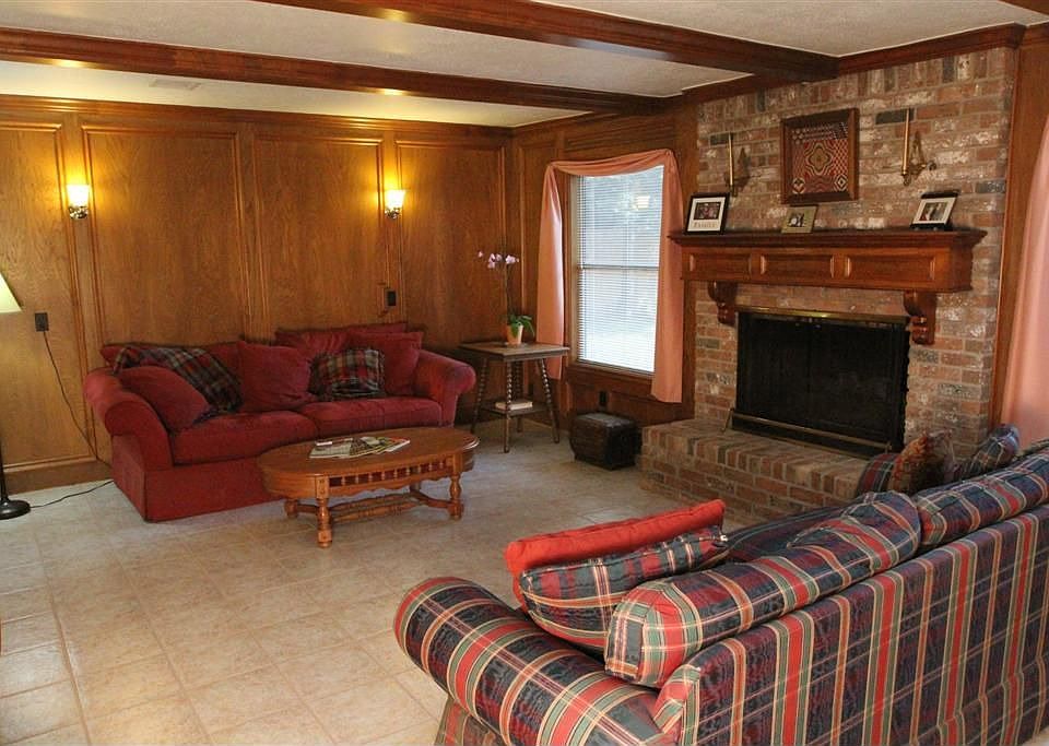 Large den w/ tile floors & fireplace w/ wood paneling to match ceiling beams