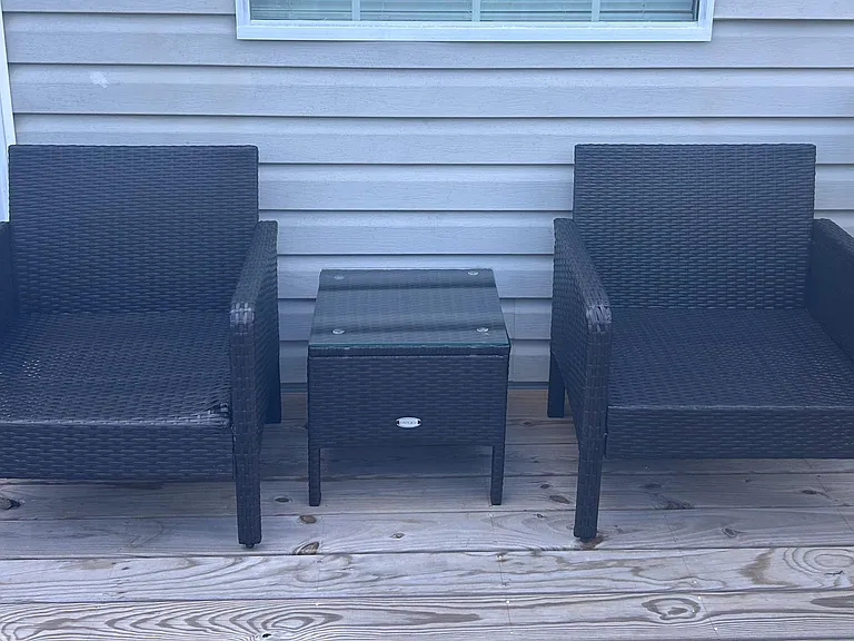 Porch seating area with two outdoor lounge chairs and a side table for relaxing or reading outdoors.