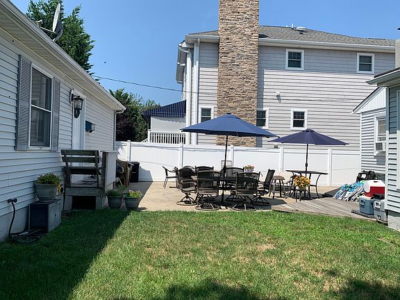Side View of front of house w/ shared patio, umbrellas make cozy shade spots. Solar lighting on both umbrellas illuminate at night.