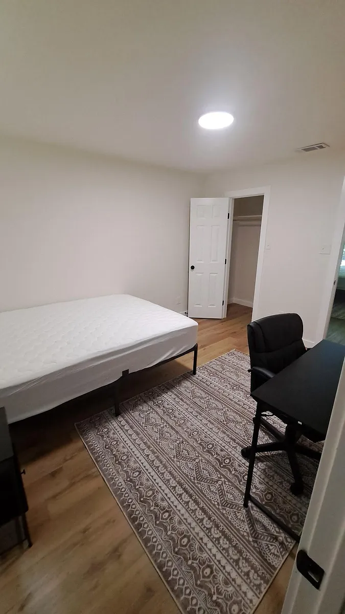 Private bedroom with wood-style floors, area rug, and furnished workspace. Includes a closet for convenient storage. - Brook Crest Rd