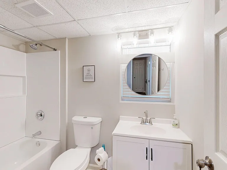 Clean full bathroom with tub/shower combo, vanity storage, and updated lighting with a wall mirror.