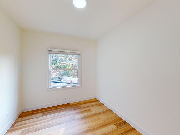 Bedroom with a window that allows natural light to filter in and floor that is made of wood