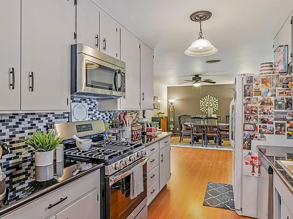 UPDATED kitchen featuring stainless steel appliances, laminate flooring, granite countertops, and stylish backsplash.