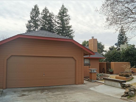 Spacious two car garage with storage space and side exterior door to back patio and trash and recycling cans.