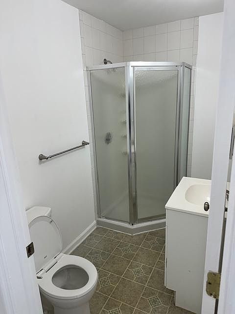 Bathroom with corner stall shower. White fixtures and vanity.