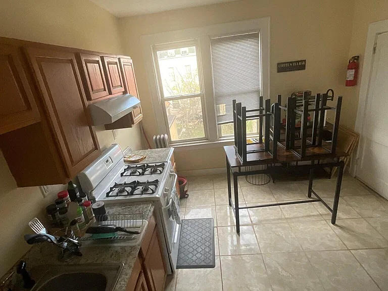 Compact eat-in kitchen with gas range, ample upper cabinets, and large windows providing natural light and ventilation.