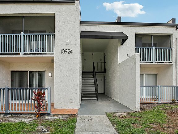 Charming apartment exterior with private balconies and a welcoming entryway, featuring a contemporary design and lush greenery.