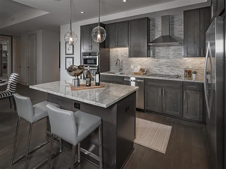 Large kitchen island with hardwood flooring and dark cabinets