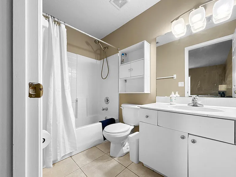 Full bathroom with tub/shower combo, large vanity countertop, and mirrored cabinet storage for everyday essentials.