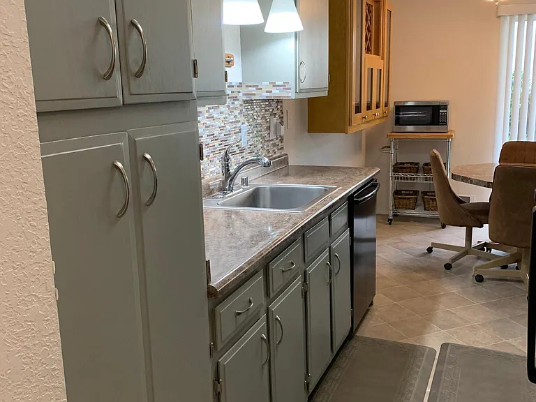 Stainless steel sink, Bosch extra quiet dishwasher, full length backsplash, hanging hooks above sink, baking sheet organizer, tall 4-door pantry, wine cabinet, microwave on moveable cart with 6 rattan baskets. Remote or motion activated under cabinet li