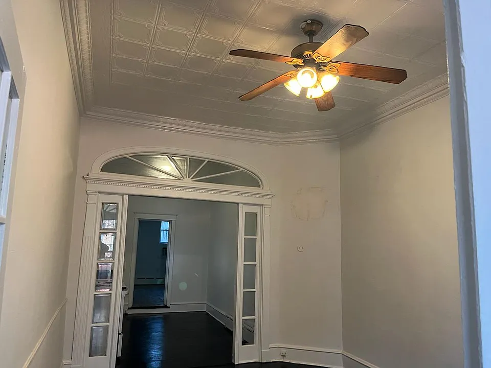 Super large living room, just painted, ornate metal ceiling with ceiling fan beautiful architectural entrance with antique glass, freshly painted