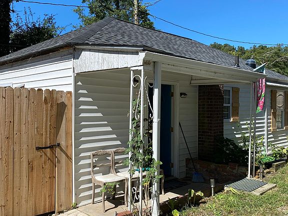 Trash and recycling bins tucked away from view behind rustic wooden fence with gate