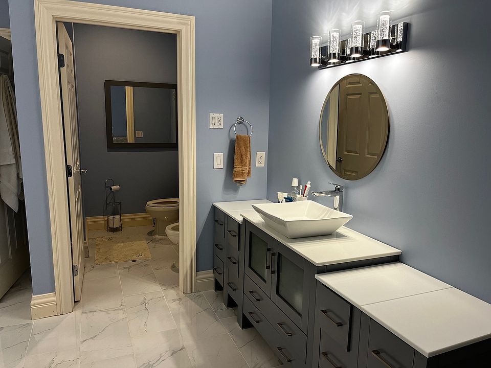 Master Bathroom with two sets of vanities on opposing walls and separate room for toilet and bidet.