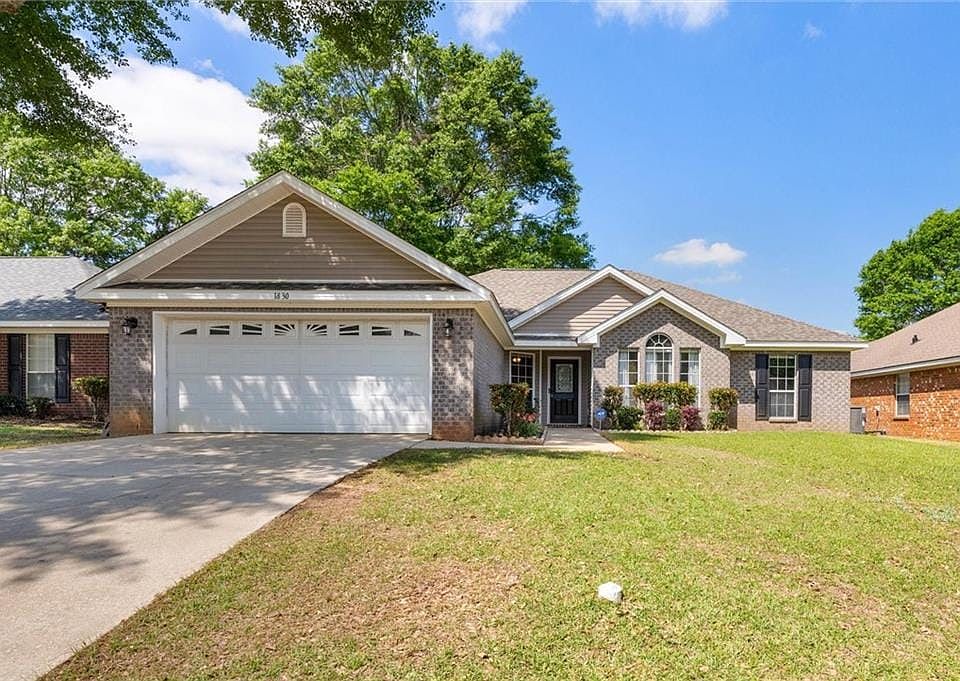Ranch-style home with brick siding, a front yard, driveway, and a garage