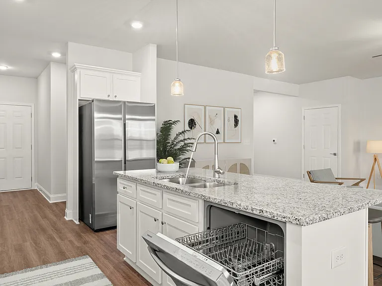 Living room with large windows that let in a ton of natural light looking into the kitchen.