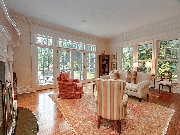 The gracious living room features a handsome fireplace, hardwood flooring and French doors