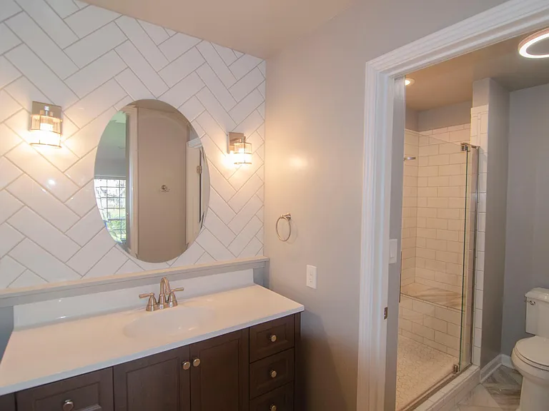 Well lit master bathroom suite with herringbone tile design