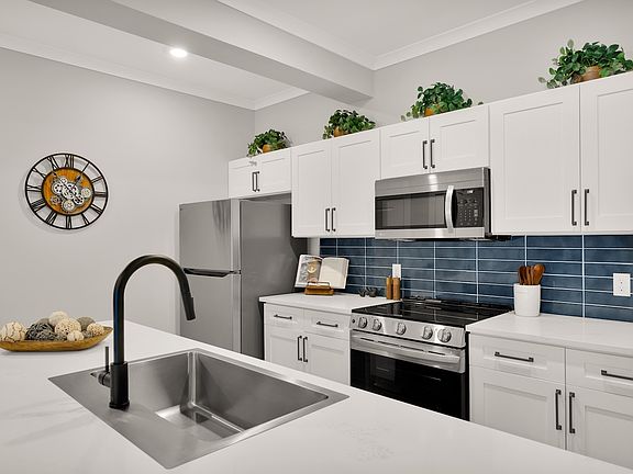 Modern kitchen with sleek stainless steel appliances, elegant white cabinetry, and a stylish island for casual dining.