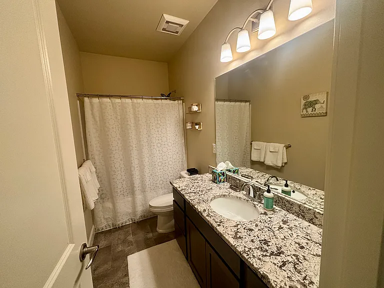 Guest bath has granite countertops, bull tub/shower combo, and large vanity