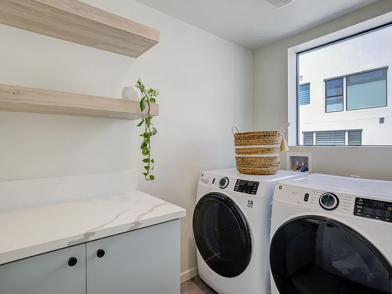 Dedicated laundry room with a door for privacy, natural light from a window, and additional storage space - Second Floor