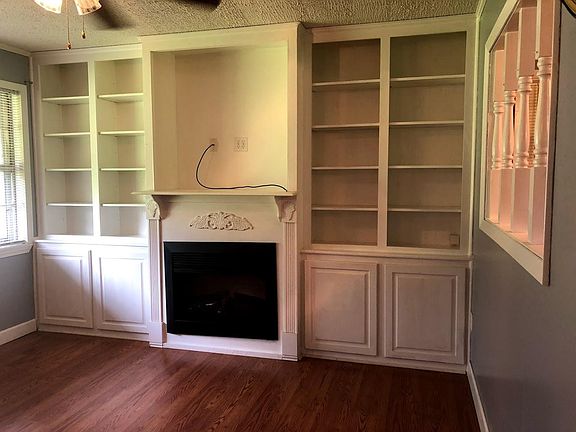Built in fireplace, entertainment center, storage, and bookshelves. View into kitchen eating nook.
