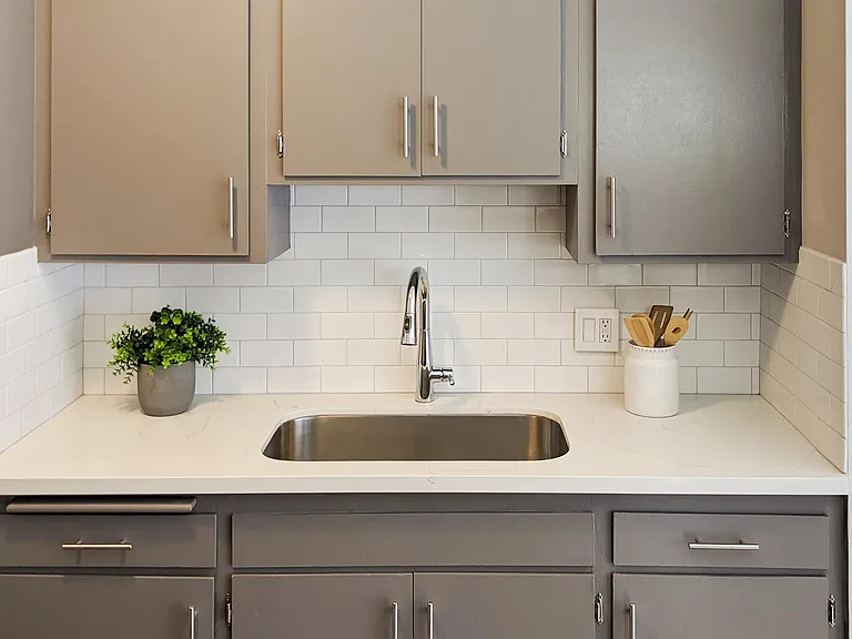 Updated quartz countertop, tile backsplash, single basin sink and faucet
